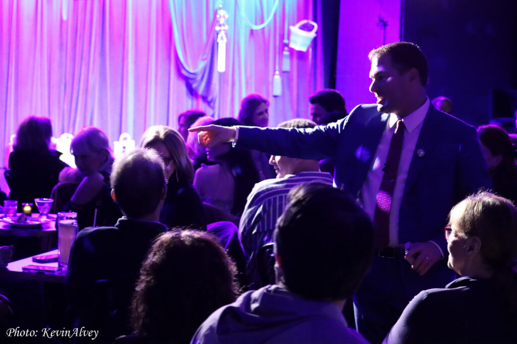 Michael in the crowd during a show. There are purple lights and Michael is pointing into the distance