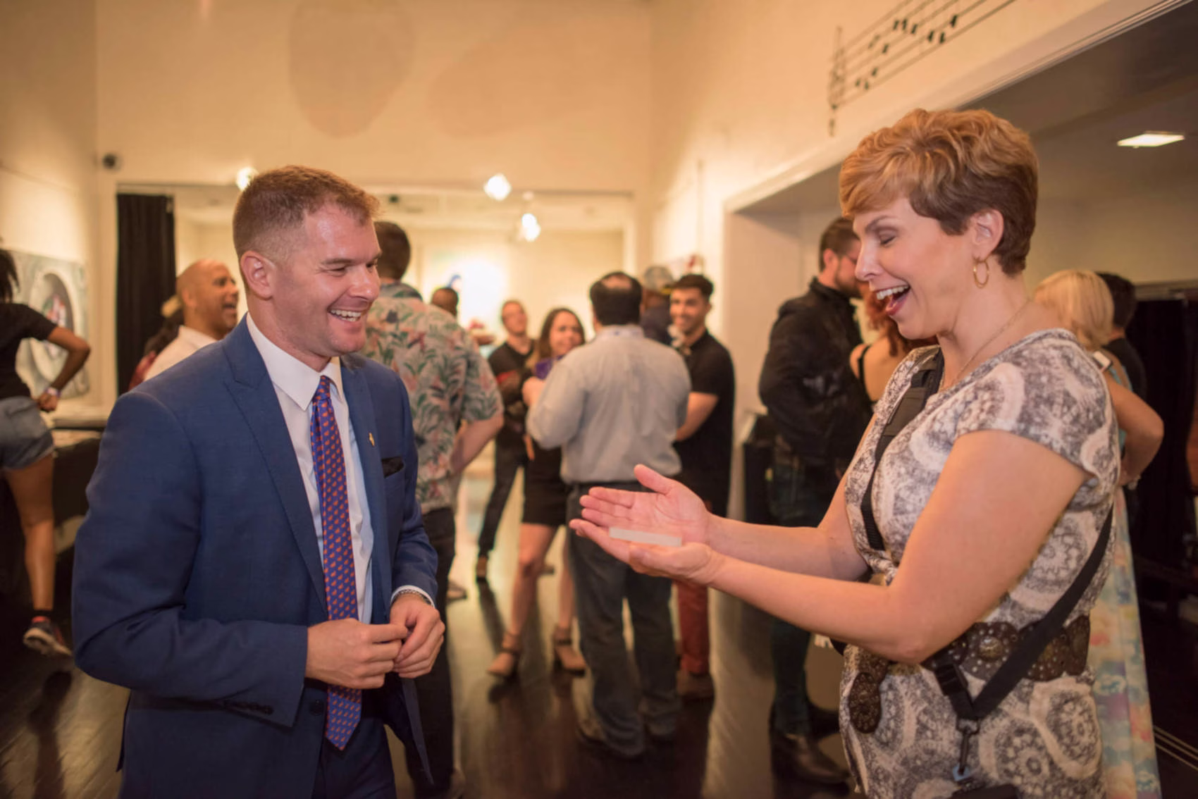 An image of Michael Gutenplan, magician, doing a card trick for a woman at an event.