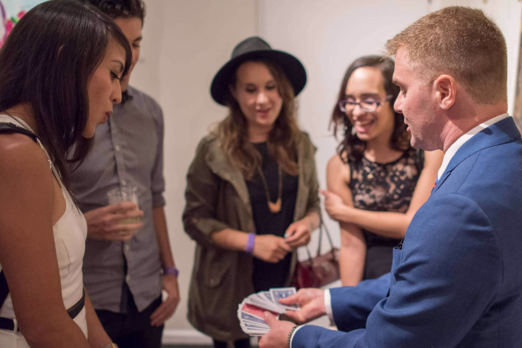 Magician Michael Gutenplan is performing a card trick for a group of delighted guests.