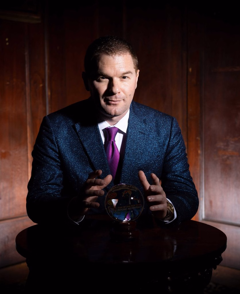 A studio portrait of Michael looking into a crystal ball.